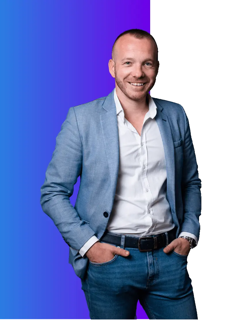 A smiling man stands with hands in pockets