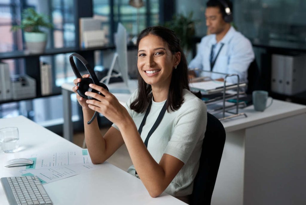 Portrait of a young woman using a headset and computer in a call center