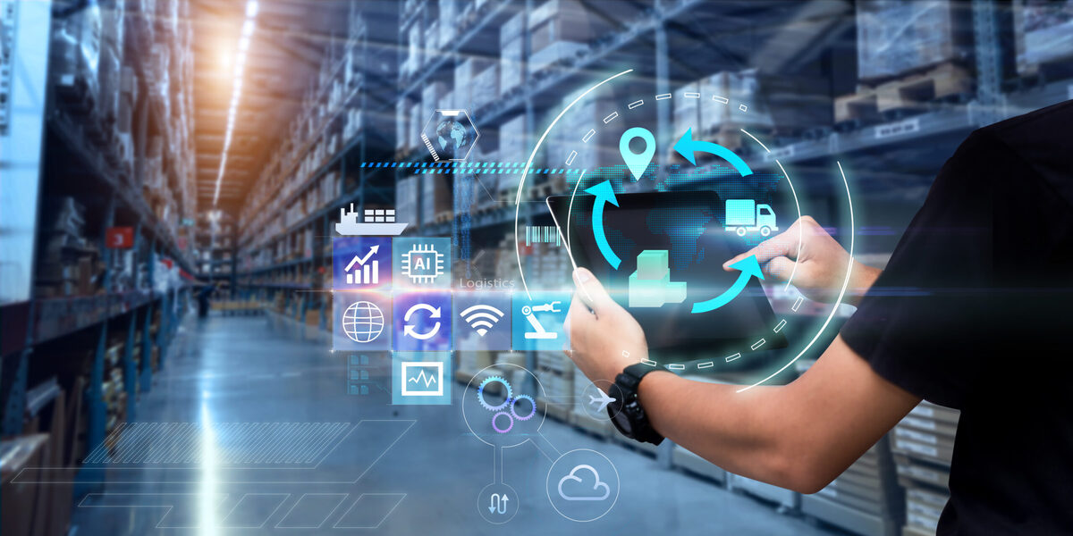 Man hands using tablet on blurred warehouse as background representing hero image for the blog about The Hidden ROI of Logistics Outsourcing Services